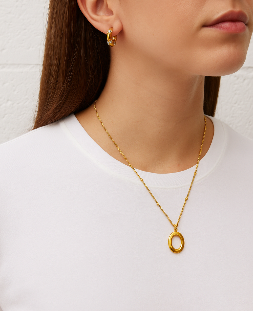 Woman wearing a gold necklace and earrings against a white background